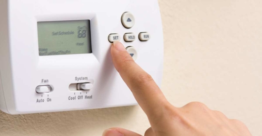 person adjusting a thermostat