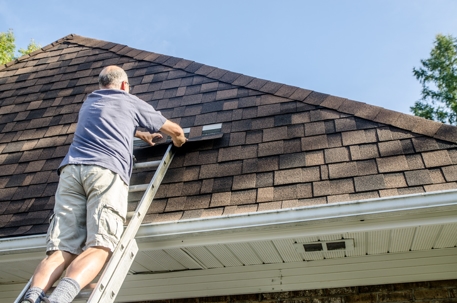 Mature man repairing asphalt shingle roof.