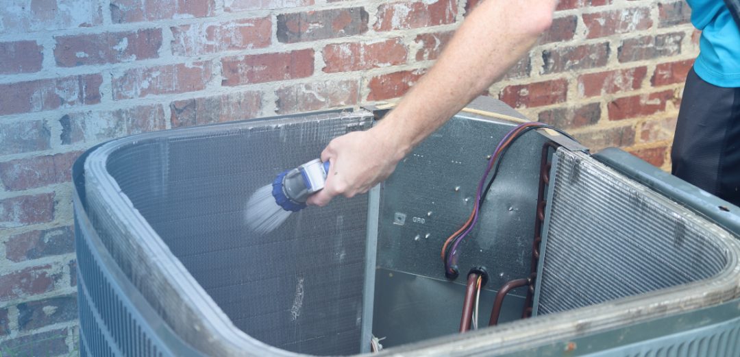 a hand cleaning the inside of a air conditioning unit with a hose