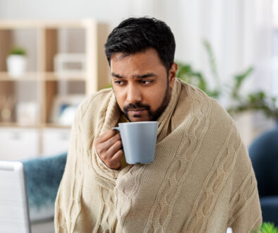 A man wrapped in a warm beige blanket drinking coffee