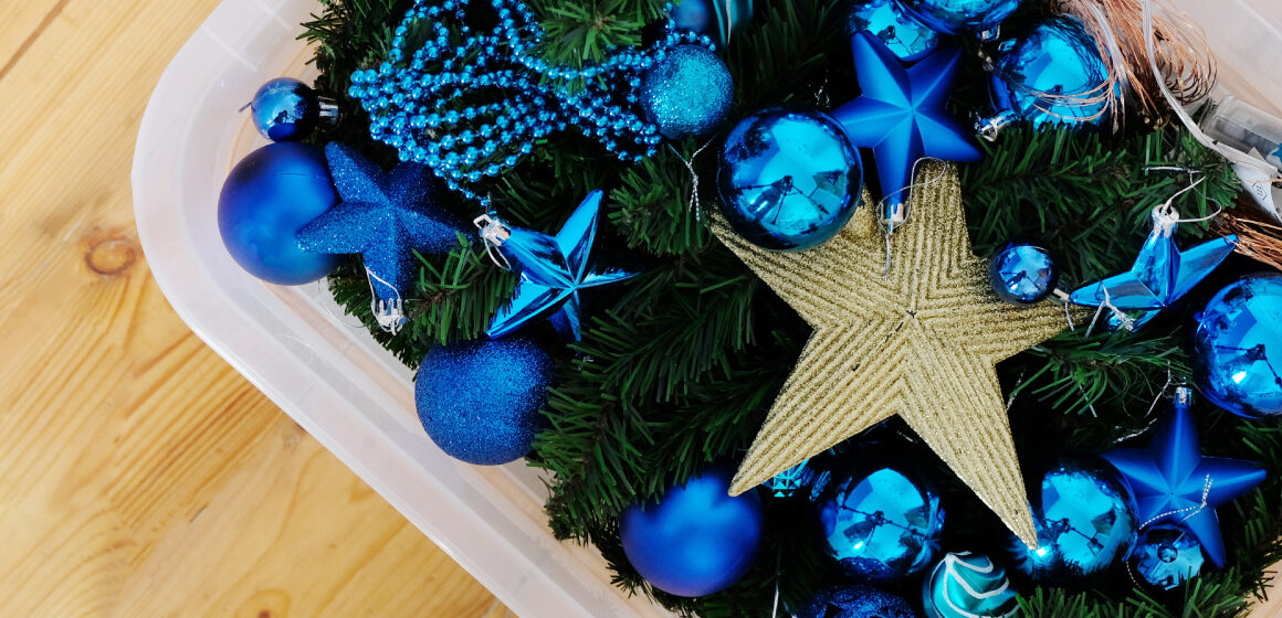 A plastic container on the floor with a fake christmas tree and blue ornaments inside